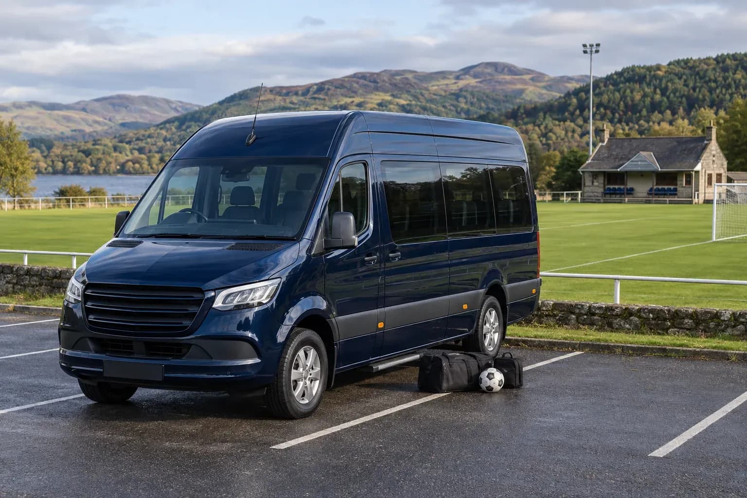 An executive minibus with kit bags beside a Scottish sports ground